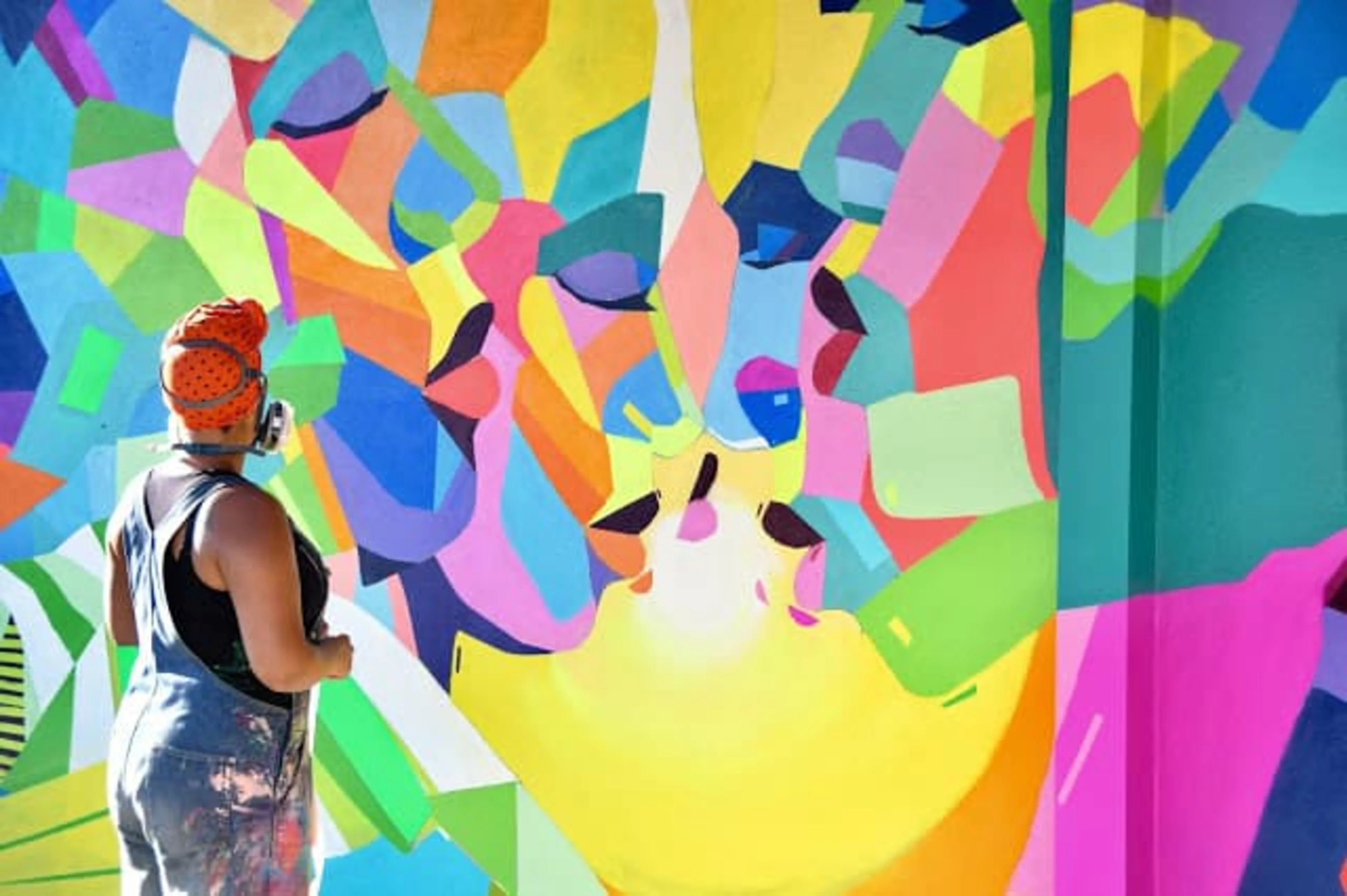 A woman spray painting bright, colorful mural