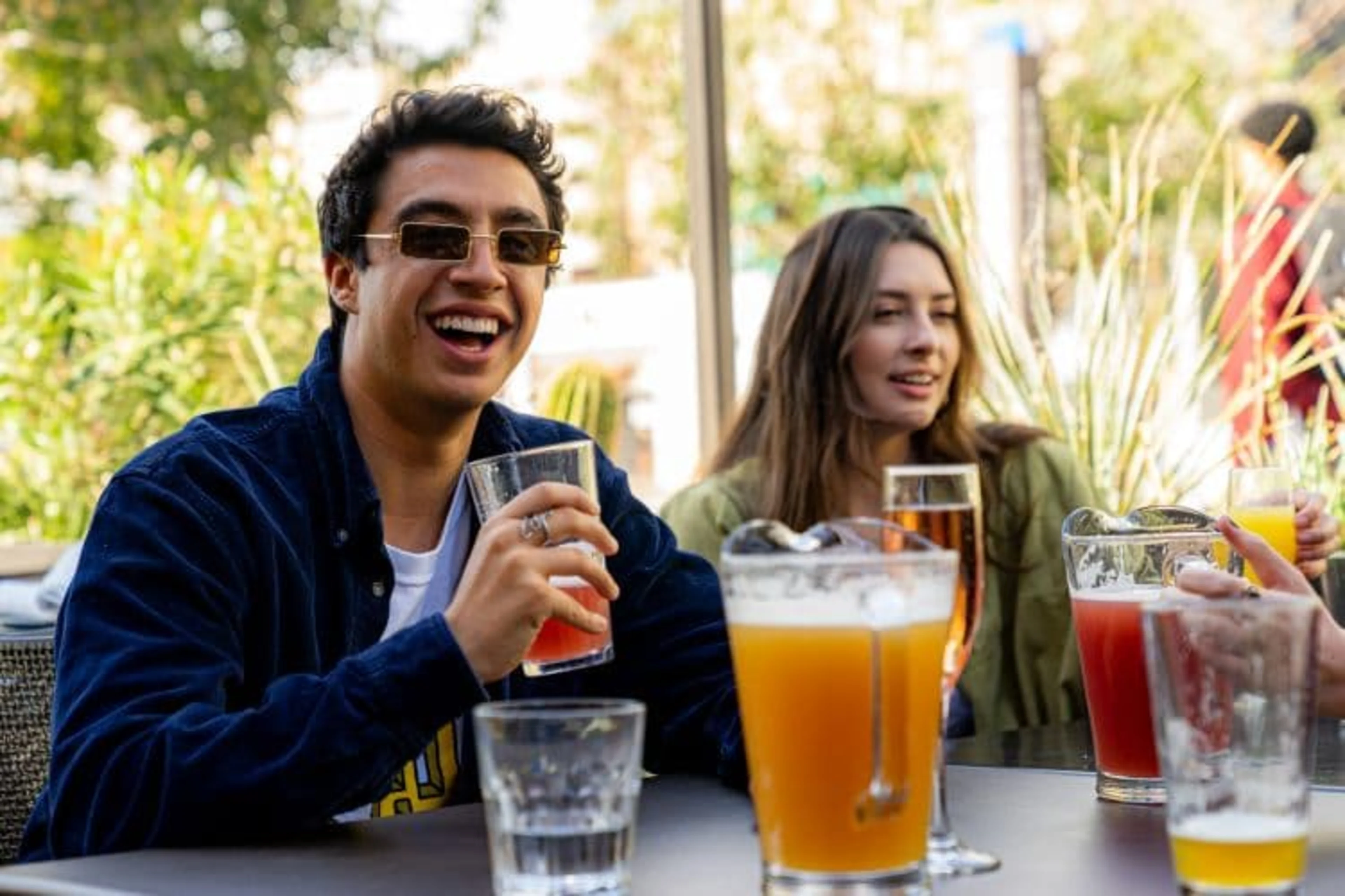 Two young people drinking a pitcher of beer and smiling.