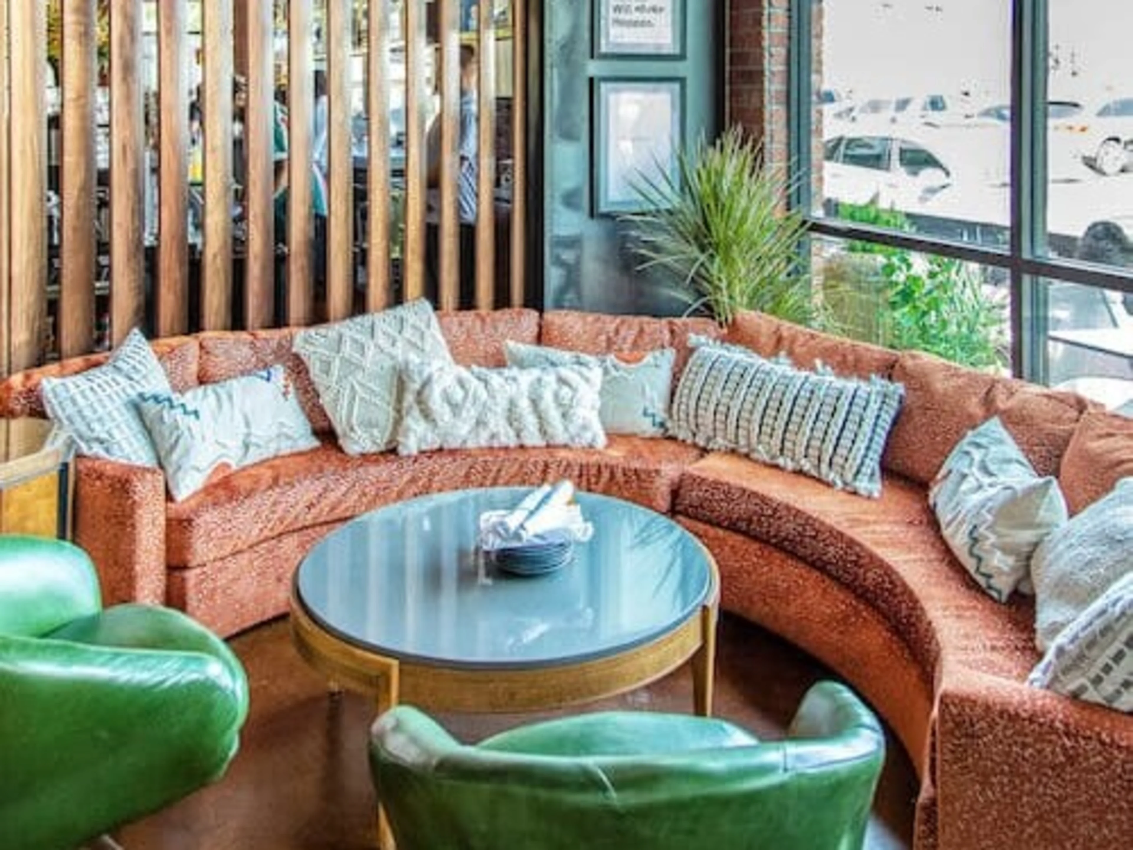 A large, empty restaurant with orange sofas and large colorful chandeliers.