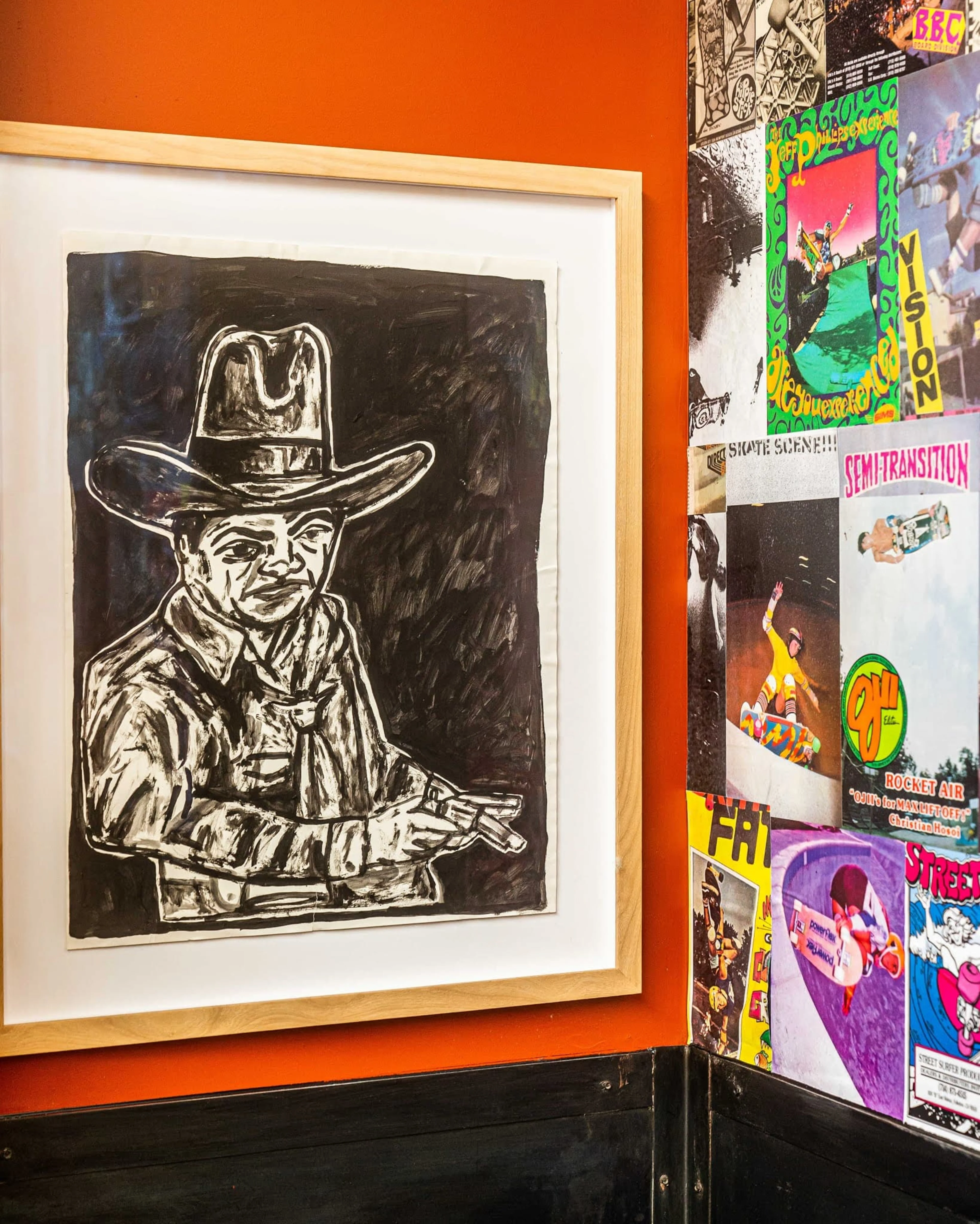 A red wall with a charcoal drawing mounted on it.