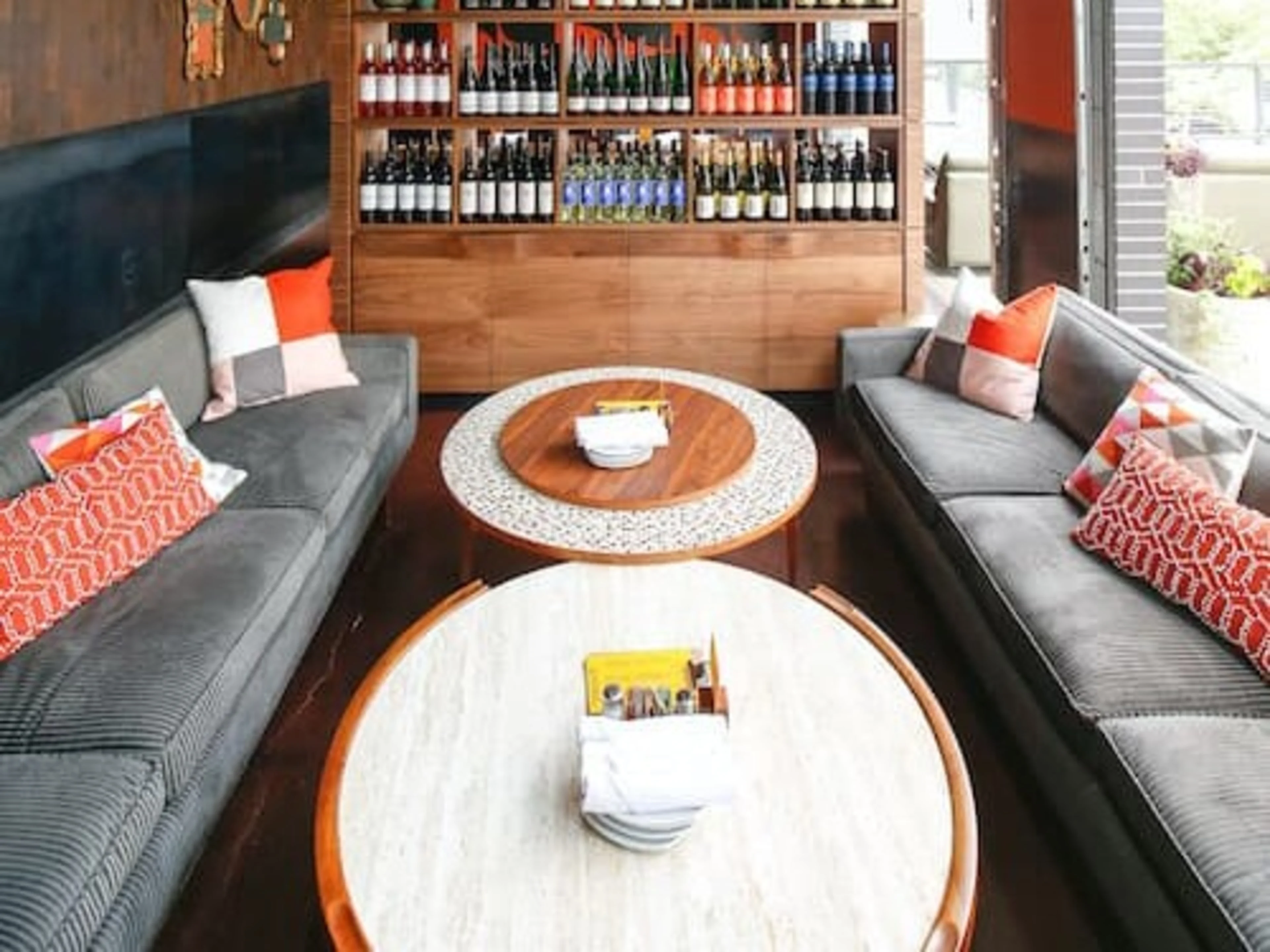 A large, colorful glass chandelier over grey couches.