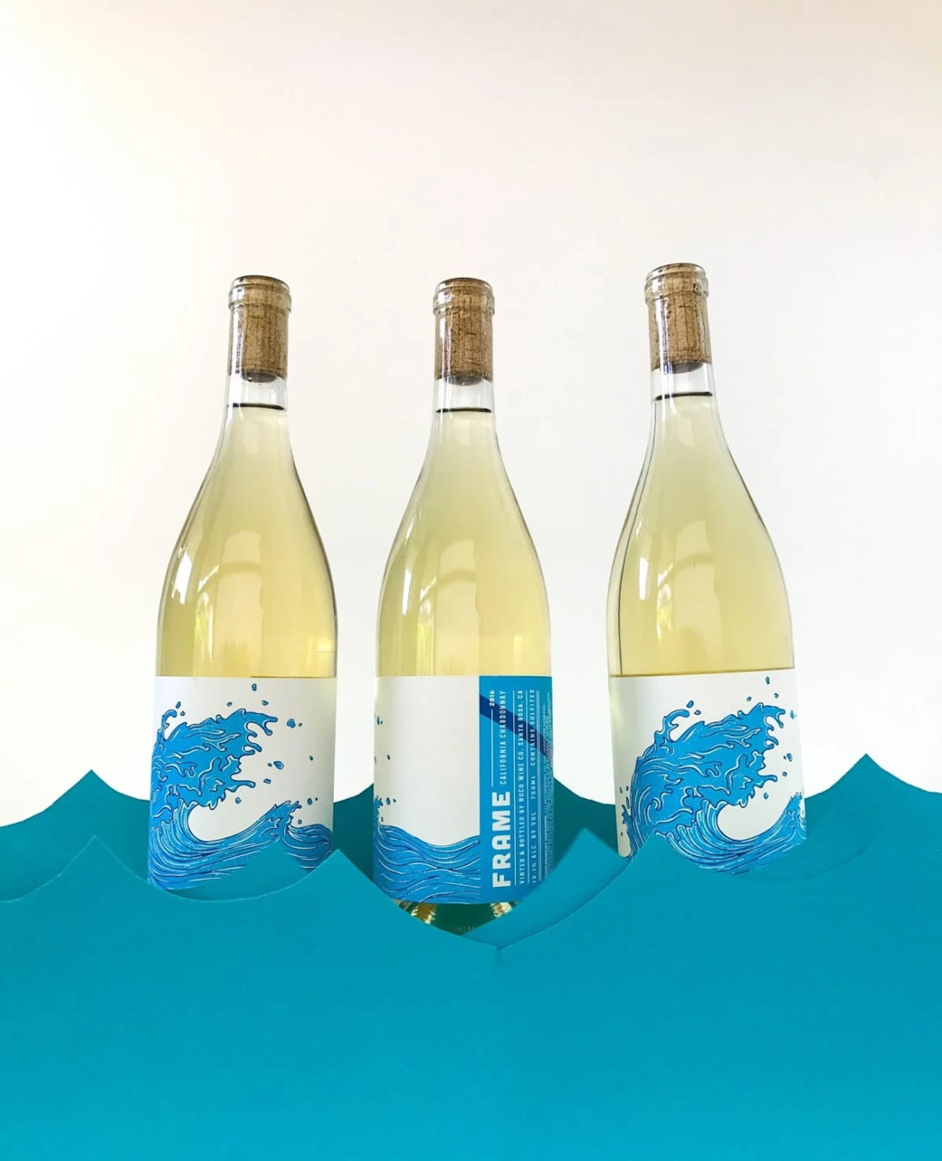 Three bottles of white wine on blue waves.