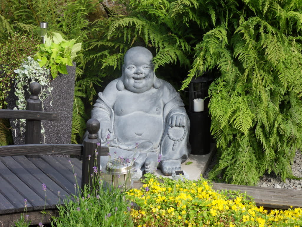 En glad och god Buddha mediterar i Lena Karlssons trädgård.