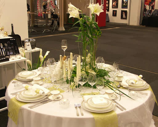 Duka hade dukat upp ett festbord på mässan med vit duk och limegröna avlånga bordstabletter. Blomsterarrangemanget med rosor, orkidéer och liljor är fiffigt, gästerna ser lätt varandra.