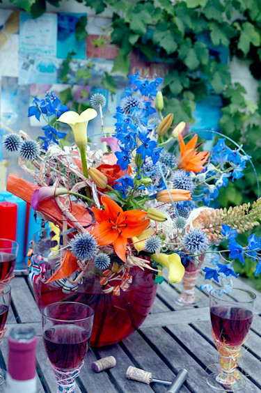 Duka upp till vårbuffé med en vild bukett av lilja, _Lilium_, riddarsporre, _Delphinium_, stäpplilja, _Eremurus_, bolltistel, _Echinops_ och kalla, _Zantedeschia_.