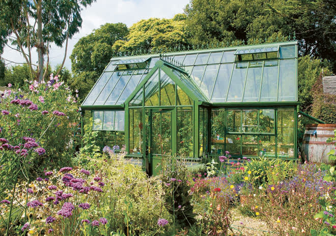 I den täta grönskan smälter ett grönt växthus in fint. 
Foto: Vansta Trädgård 