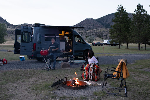 Photo of family around a campfire in front of a small RV 