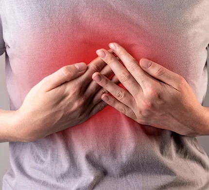 Person clutching chest with both hands, red glow indicating pain or discomfort in the chest area.
