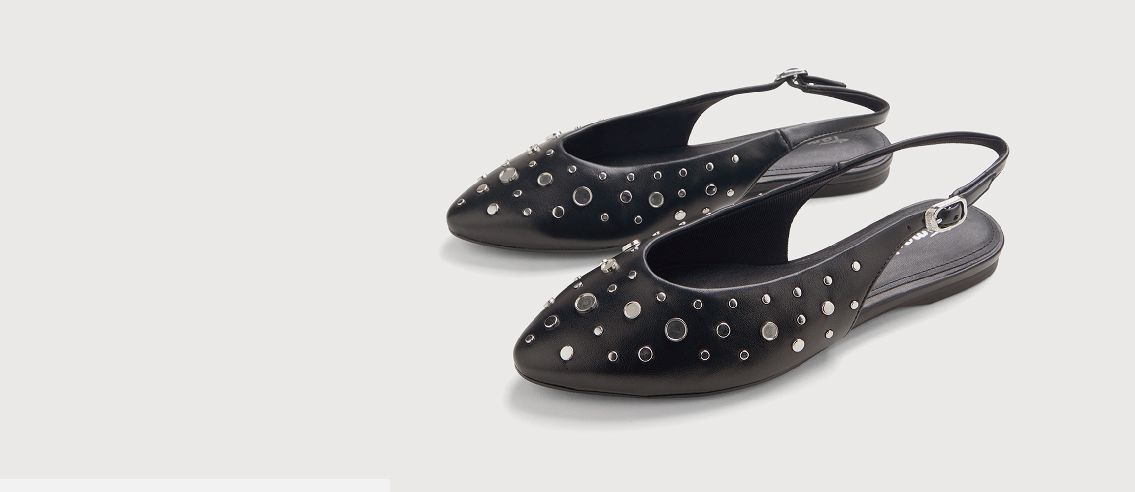 Black slingback ballet flats with silver studs and eyelets, flat sole, adjustable heel strap, pointed toe.