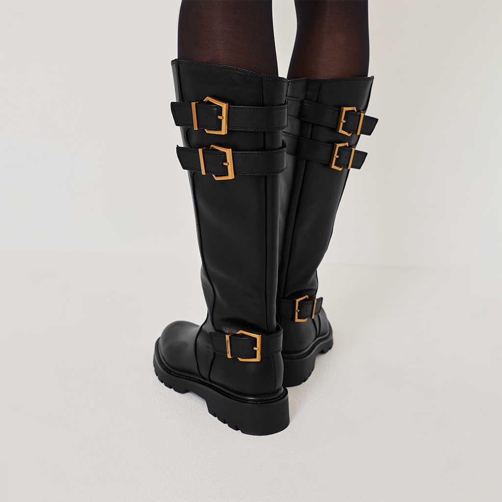 Schwarze Lederstiefel mit goldenen Schnallen, mehrere Riemen am Schaft, kniehoher Schnitt und robuste Profilsohle