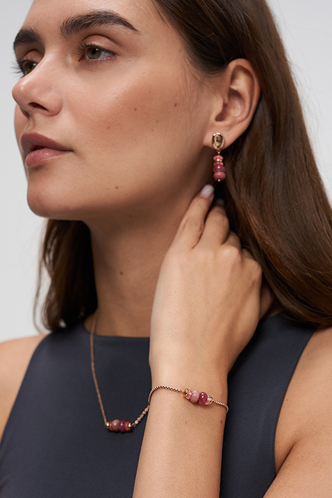 Gros plan sur des bijoux roses port&eacute;s en boucles d&rsquo;oreilles, bracelet et collier.