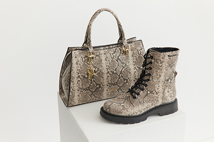 Beige Handtasche und passende Schnürstiefel mit Schlangenmuster auf weißem Hintergrund