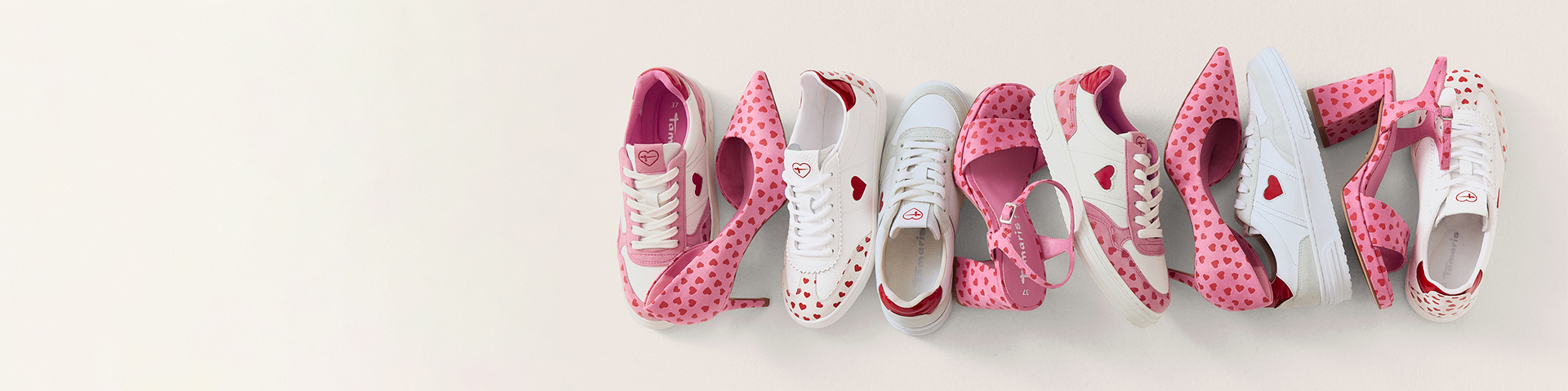 Mehrere Damenschuhe in Wei&szlig; und Rosa mit Herzmuster in einer Reihe angeordnet.