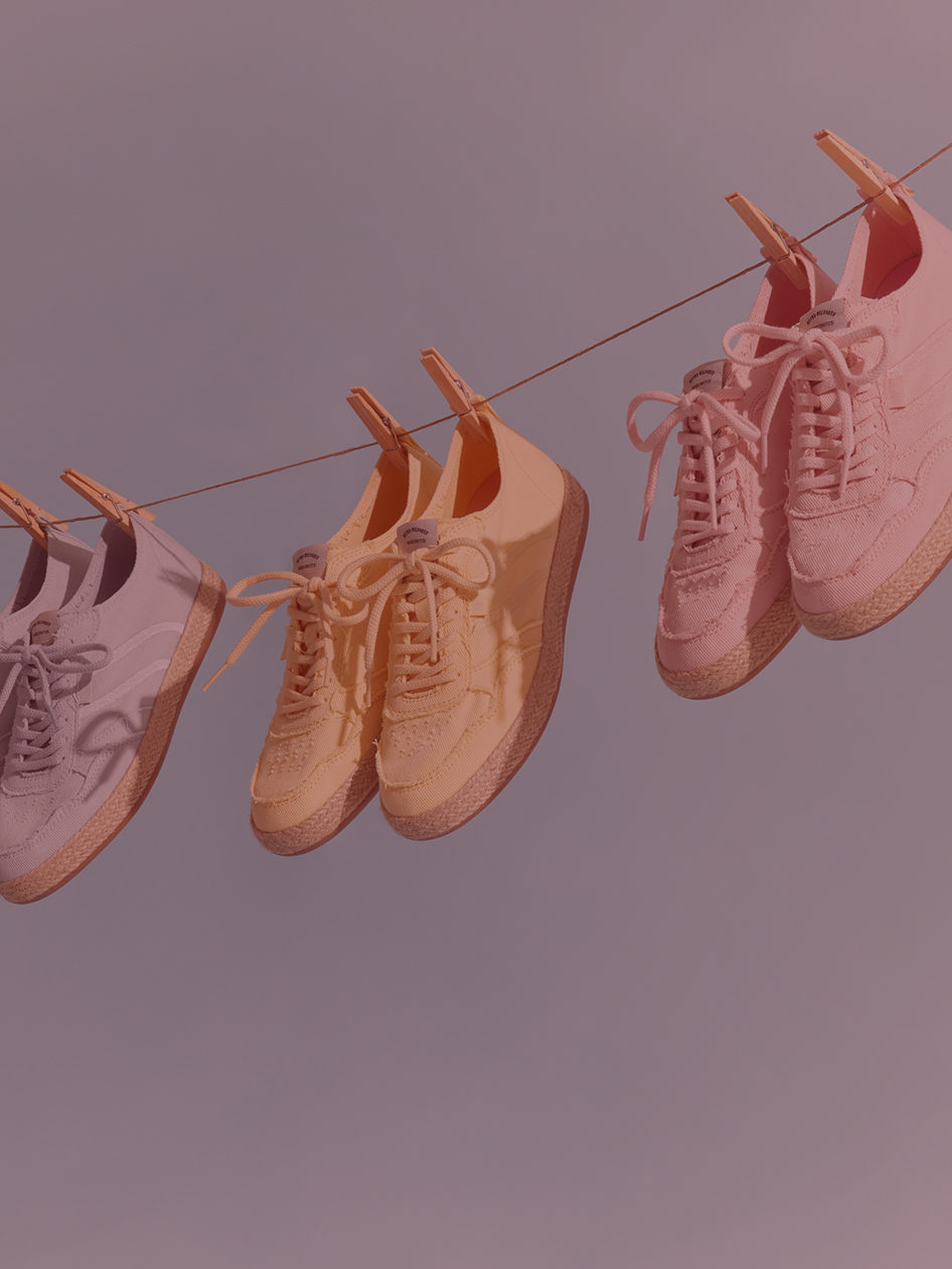 Vier Paar Sneaker in Pastellt&ouml;nen h&auml;ngen mit W&auml;scheklammern an einer Leine.