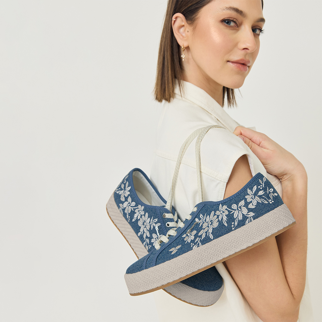 Jeans blue sneaker with a white floral pattern, showcased against a light background in an elegant model shot.
