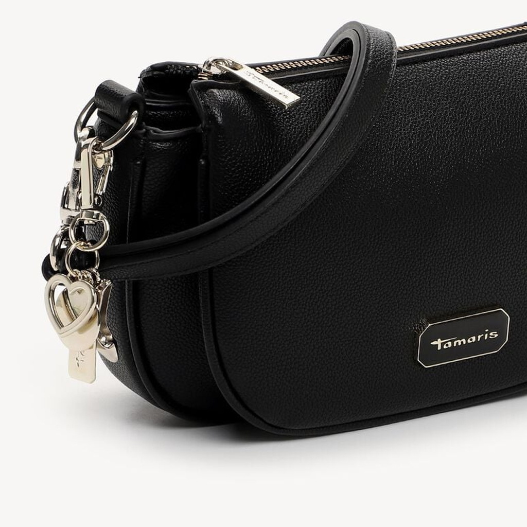 Sac noir Tamaris avec d&eacute;tails m&eacute;talliques argent&eacute;s et pendentif en forme de c&oelig;ur sur la cha&icirc;ne de fermeture &eacute;clair, sur fond blanc.