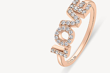 Bague en or rose avec diamants étincelants formant le mot "LOVE" en écriture incurvée.