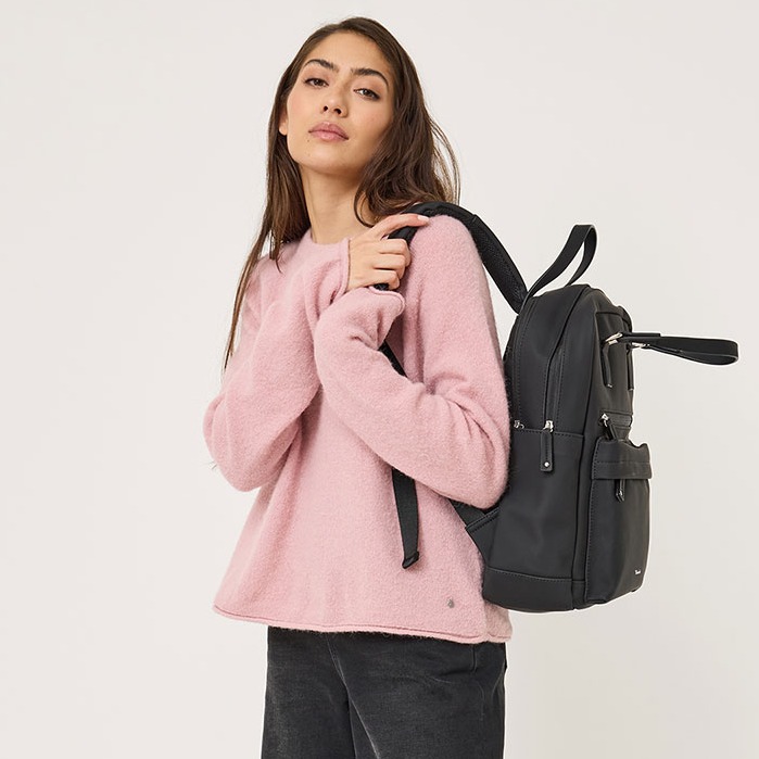 Model i lyser&oslash;d sweater og sorte bukser b&aelig;rer en sort rygs&aelig;k foran hvid baggrund