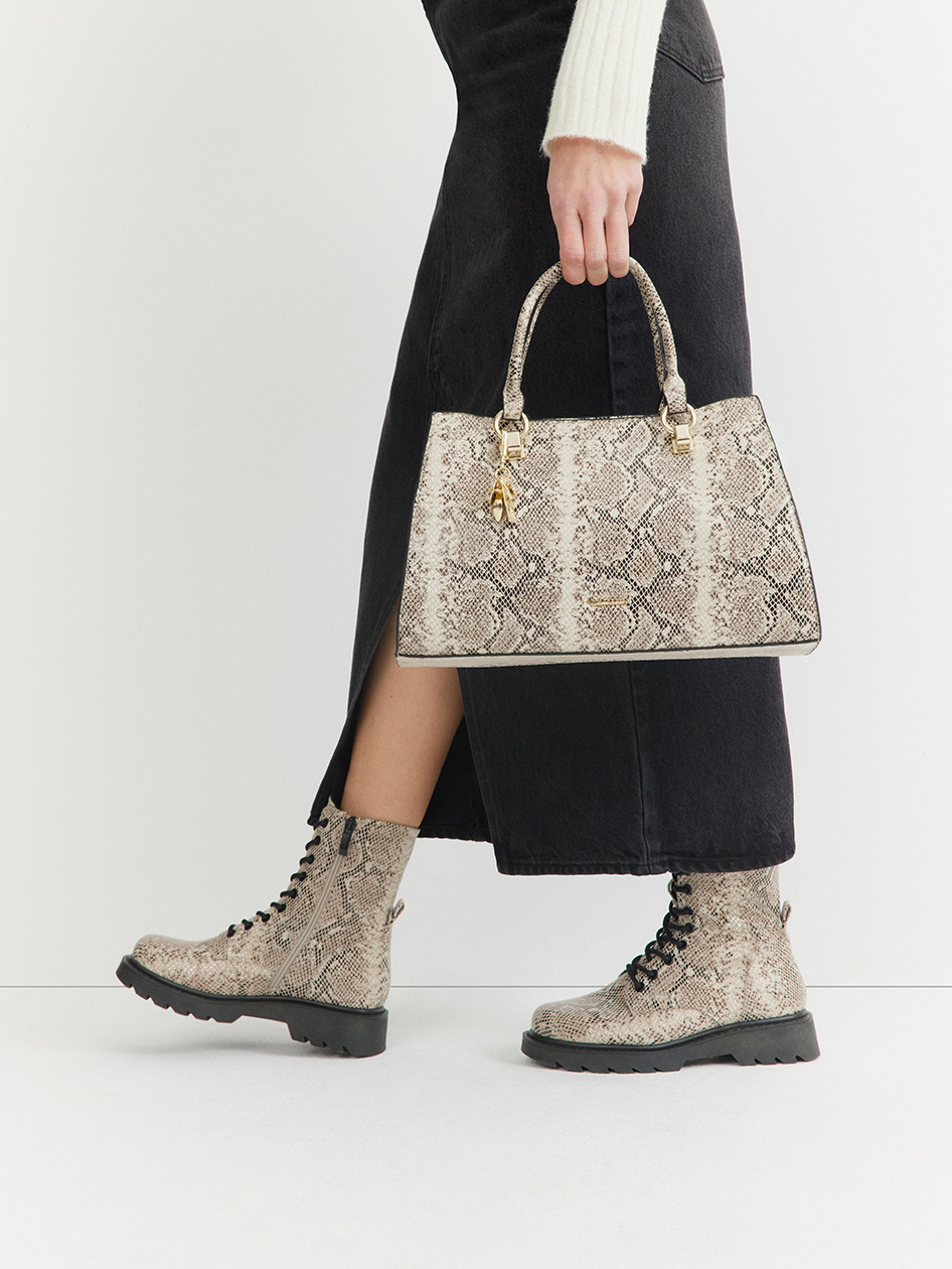 Sac à main et bottes à imprimé serpent assortis à une jupe noire et à un pull blanc.