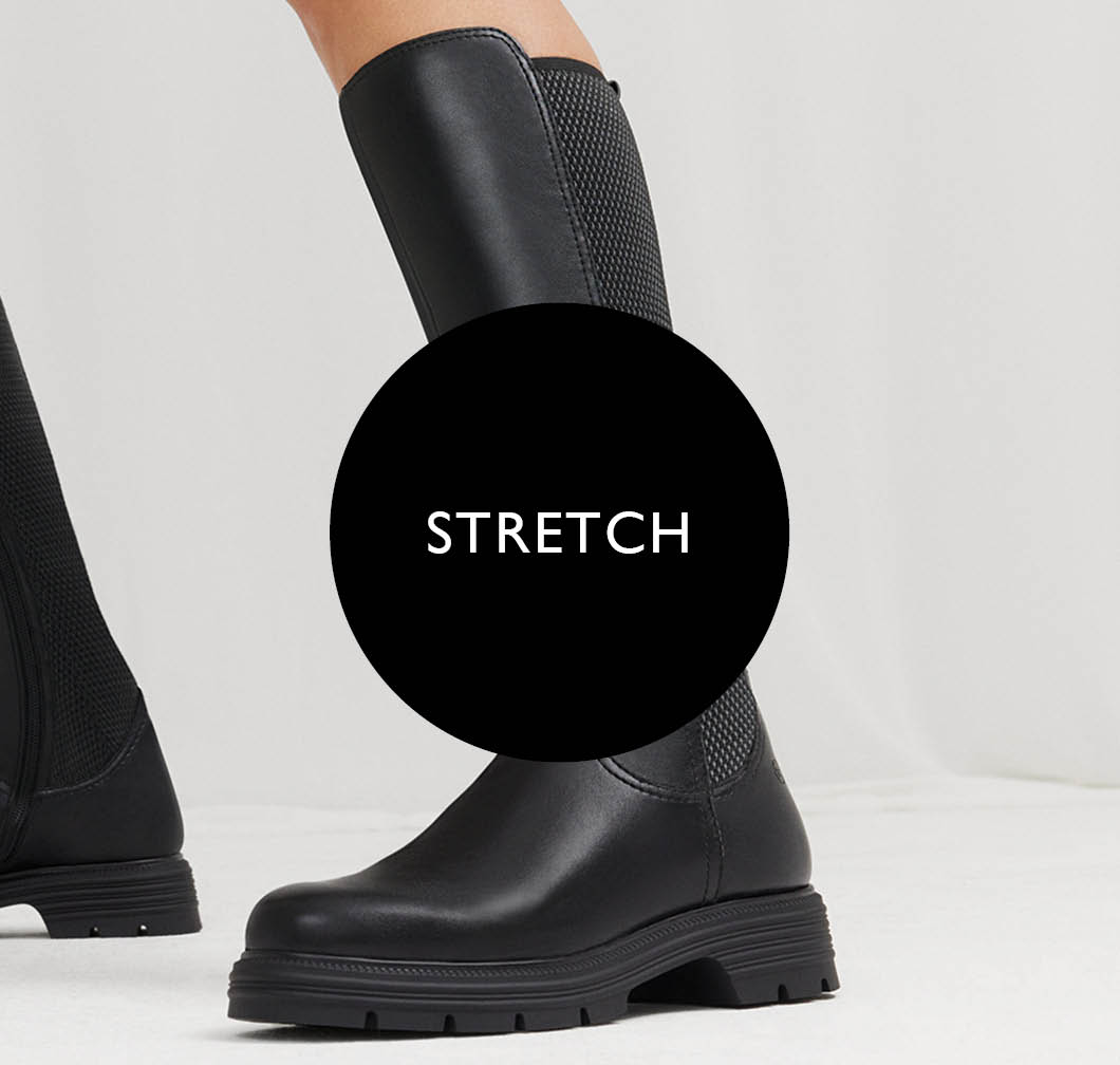 Black leather stretch boots with a treaded sole on a white background, with a black circle on top bearing the word &ldquo;Stretch&rdquo;.