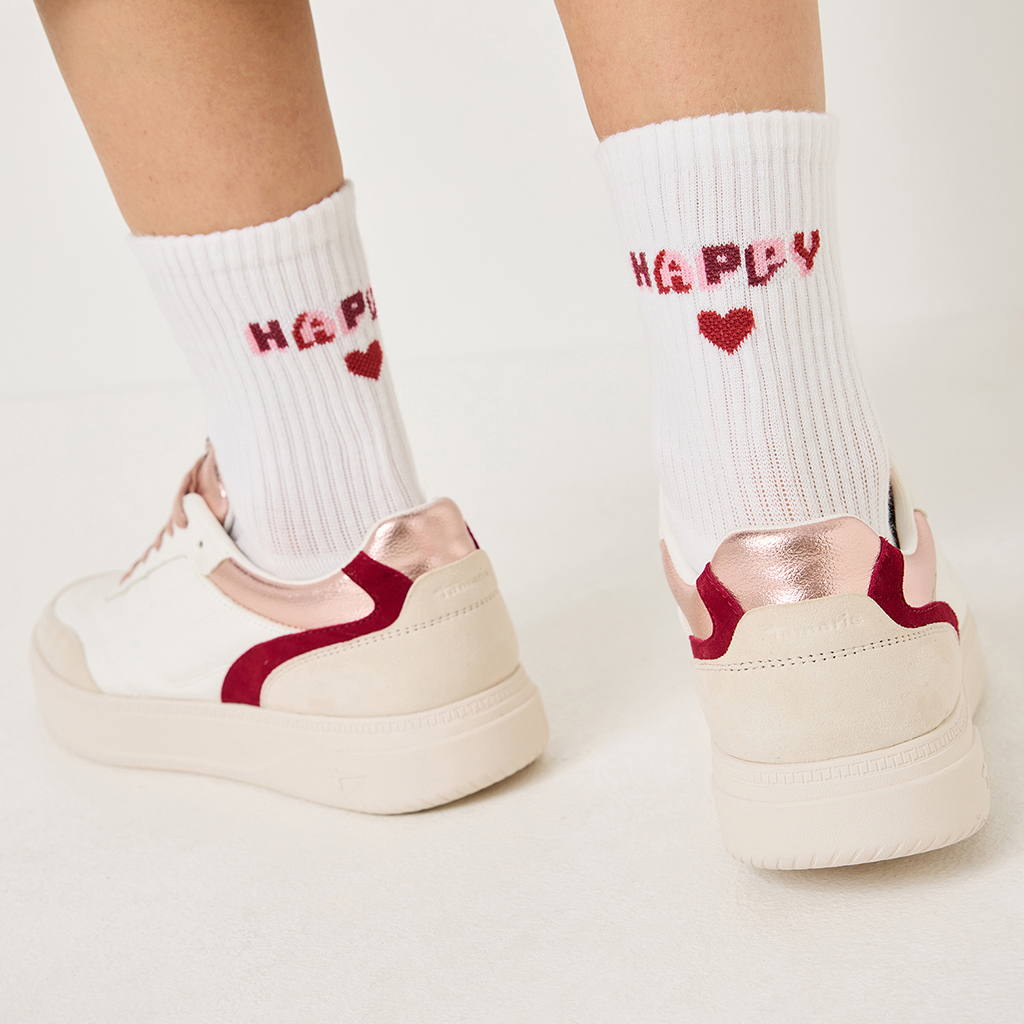Vita strumpor med röd "Happy"-text och hjärtan, bärs med vita sneakers med röda accenter