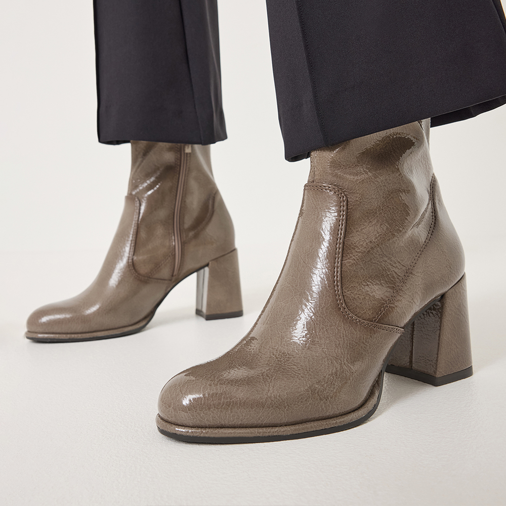 Stivaletti in vernice lucida color taupe con tacco a blocco, indossati con pantaloni neri