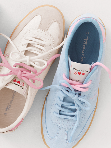 Des sneakers dans des tons pastel blanc, rose et bleu ciel avec des lacets, sur fond blanc.