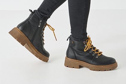 Black lace-up ankle boots on a light floor