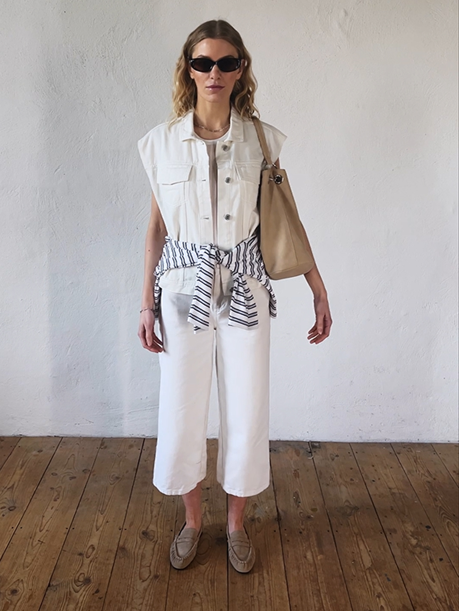 Donna con outfit marinaro beige. Indossa boat shoes coordinati e una borsa a spalla.