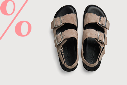 Une paire de sandales beiges avec boucles sur fond blanc, &agrave; c&ocirc;t&eacute; de symboles de pourcentage roses indiquant des r&eacute;ductions.