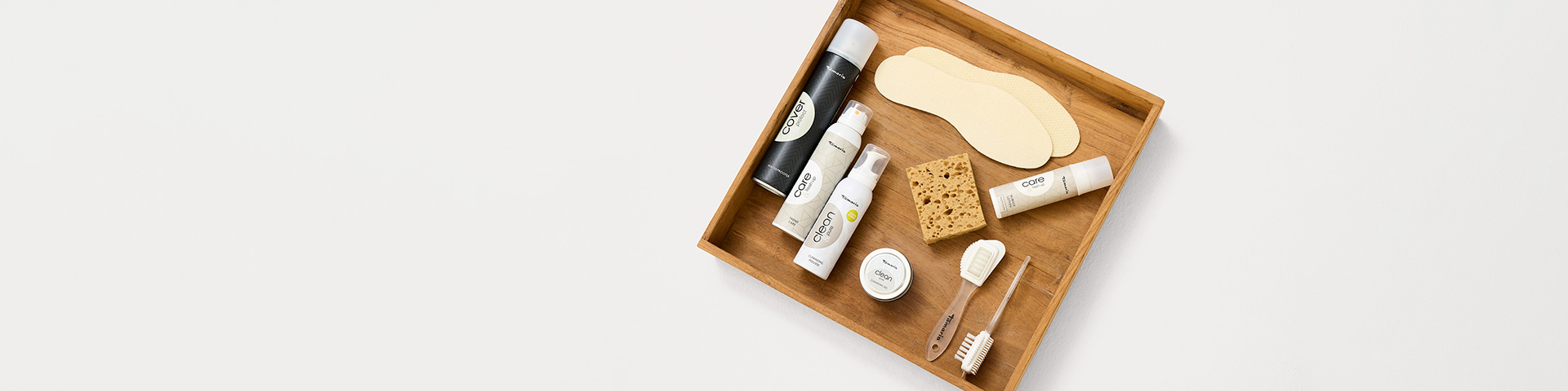 Kosmetikprodukte und Pflegeartikel ordentlich auf einem hölzernen Organizer mit Fächern angeordnet, von oben fotografiert.