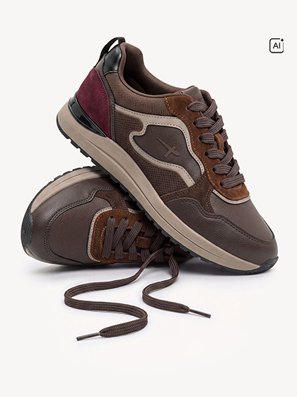 Bruine sneakers met bordeauxrode accenten en bruine veters, gestapeld tegen een witte achtergrond.