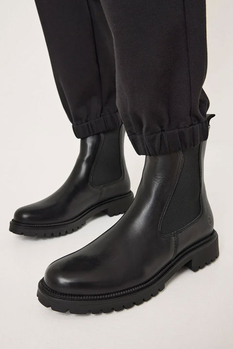 Black leather Chelsea boots with a robust treaded sole, worn with black trousers with elasticated cuffs