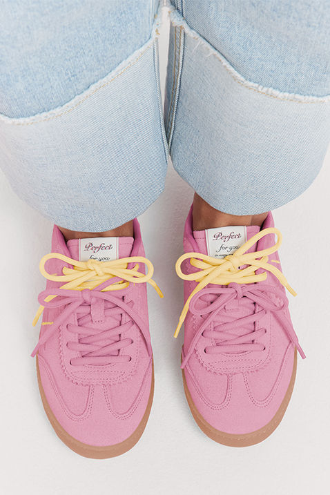 Baskets roses avec des lacets jaunes et une semelle brun clair, port&eacute;es avec un jean clair