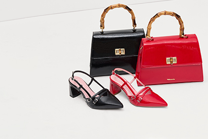 Two elegant handbags in black and red with bamboo handles, paired with matching black and red slingback pumps.
