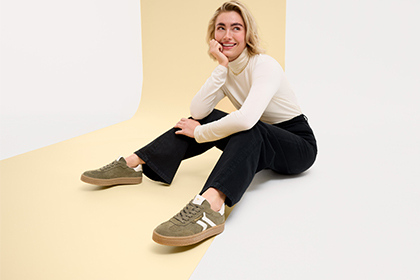 Opnamen van een persoon in een witte trui en zwarte broek, die op een beige achtergrond verschillende zittende houdingen toont.