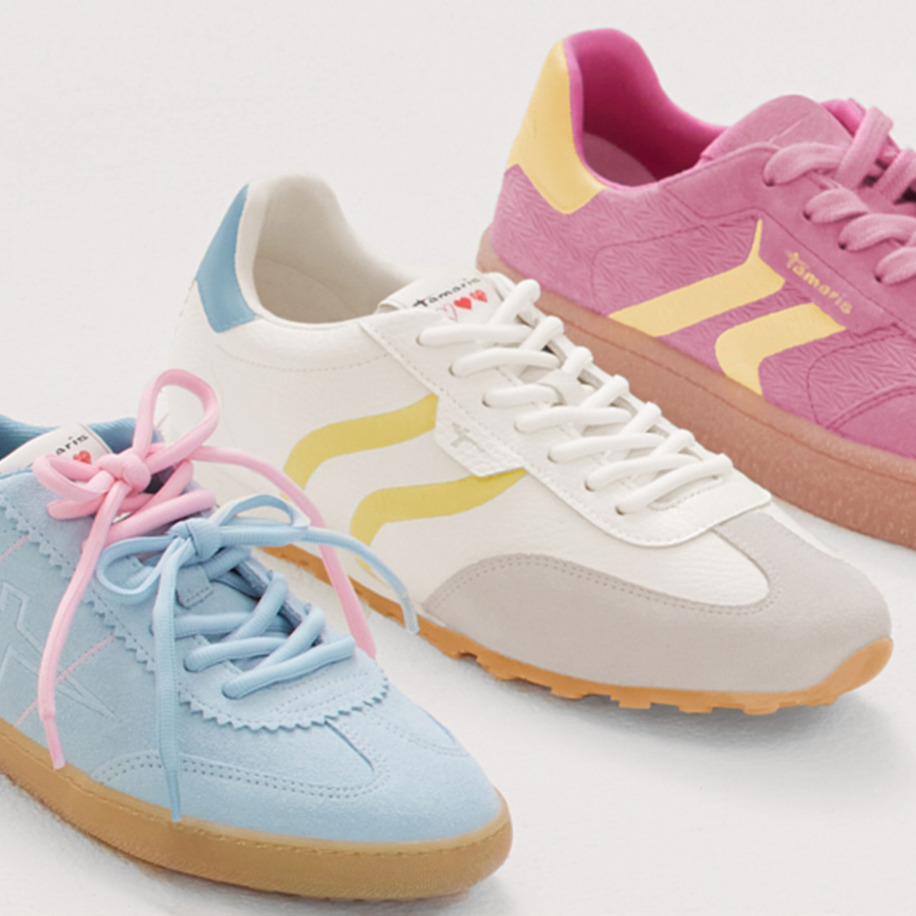 Three fashionable sneakers in pastel colors &ndash; light blue, white and pink &ndash; arranged in a row.