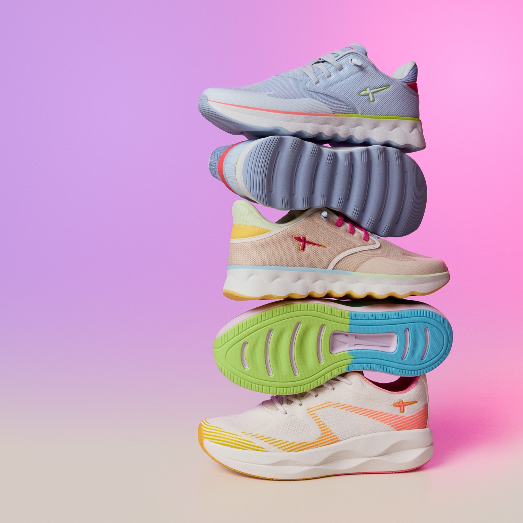 Staplande sportskor i pastellf&auml;rger mot en rosa-lila bakgrund, med f&auml;rgglada sulor och modern design