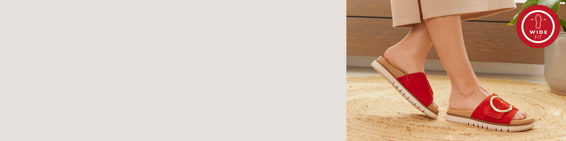 Röda damsliplockar med guldfärgat spänne på en beige matta, bärs med fötterna i avslappnad position och en röd vid passformslogga i det övre högra hörnet.