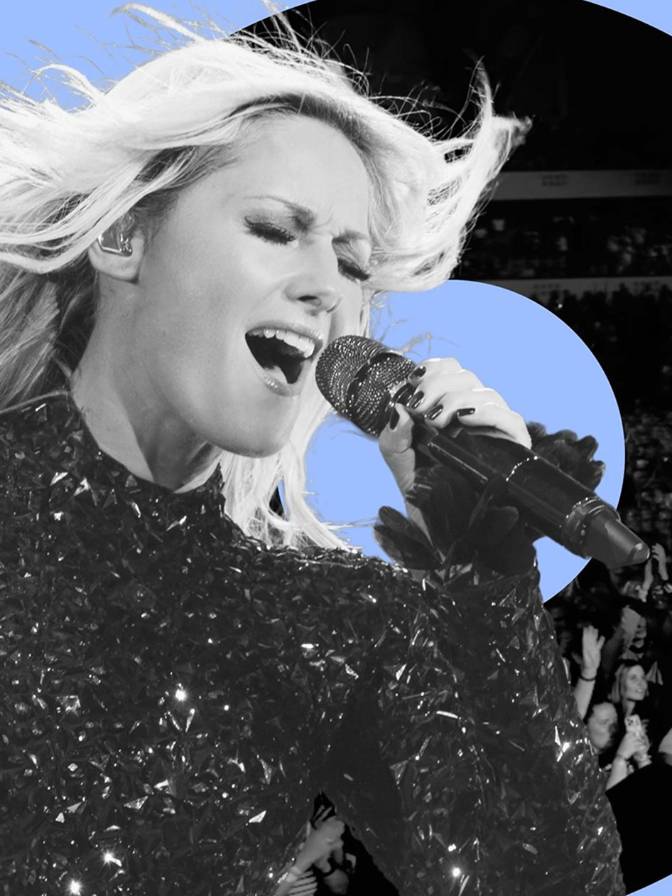 Chanteuse dynamique en tenue noire scintillante chantant avec passion dans le micro, ses cheveux blonds flottant au vent.