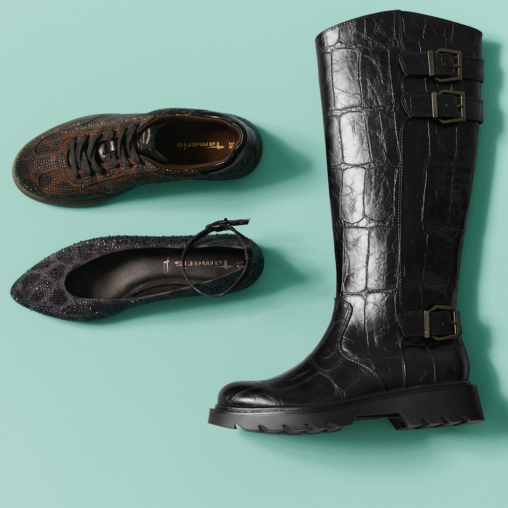 Schwarze Lederstiefel mit Schnallen und braune Glitzer-Ballerinas auf türkisfarbenem Hintergrund