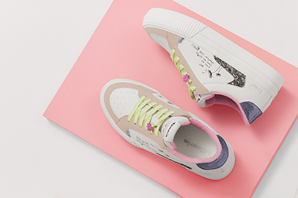 Sneakers bianche con lacci giallo neon su sfondo rosa.