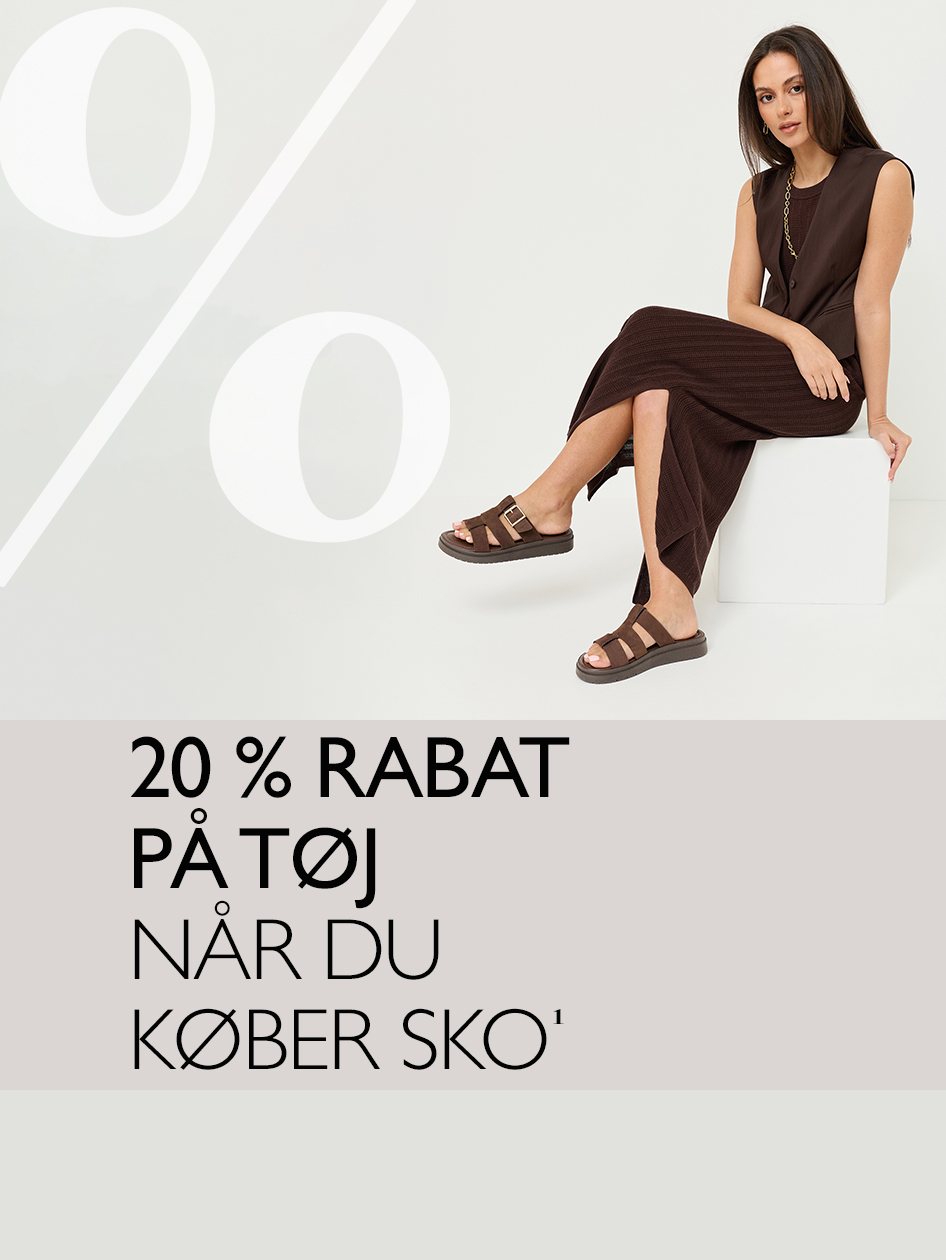 Kvinde i brunt outfit og sandaler sidder p&aring; en hvid kube. Tilbud: 20 % p&aring; t&oslash;j ved k&oslash;b af sko.