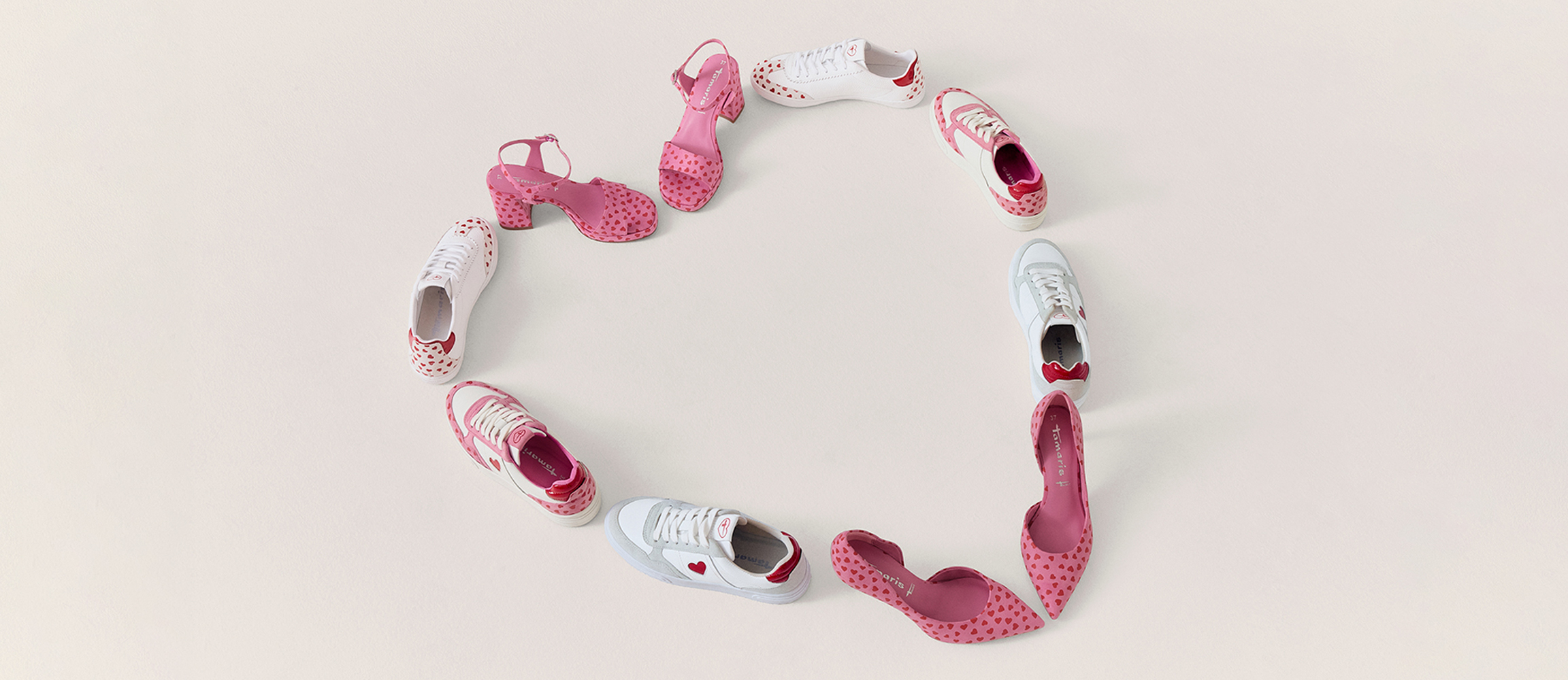 Vita sneakers och rosa sandaler med hj&auml;rtm&ouml;nster i ett hj&auml;rtformat arrangemang p&aring; vit bakgrund