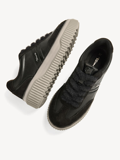 Schwarze Sneaker mit grauer Sohle in verschiedenen Ansichten, diagonal angeordnet auf weißem Hintergrund