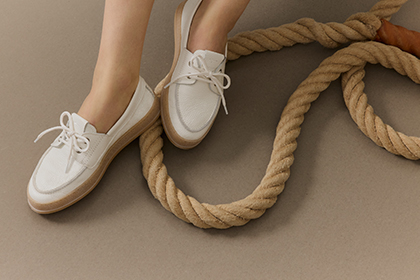 White boat shoes and a thick rope are arranged in a row on a grey background.