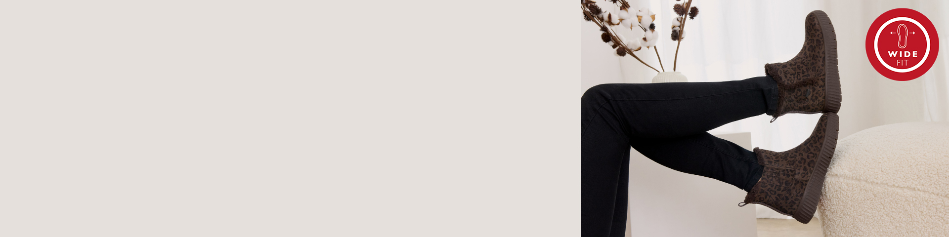 Bruine enkellaarsjes met luipaardmotief en wide-fit logo, gedragen met een zwarte broek op een lichte achtergrond met rood wide-fit logo rechtsboven