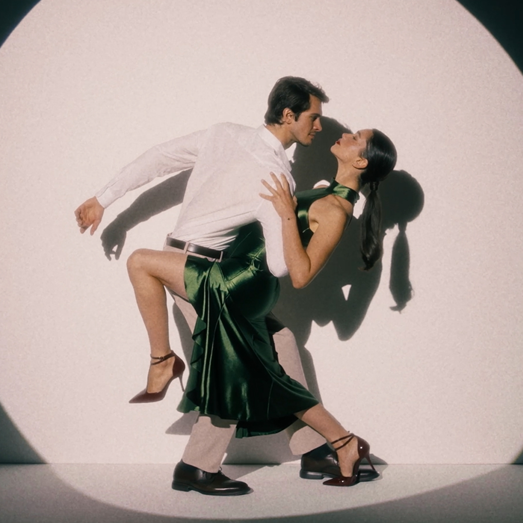 Een paar danst tango: De man in het witte overhemd houdt de vrouw in de groene zijden jurk vast in een elegante dip-pose.
