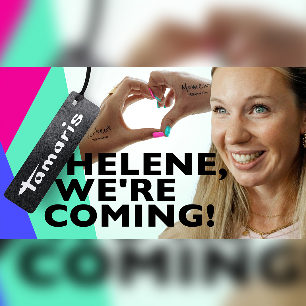 L&auml;chelnde Frau formt Herzzeichen mit H&auml;nden, bunten N&auml;geln. Tamaris-Etikett und Text &bdquo;Helene, We're Coming!" sichtbar.