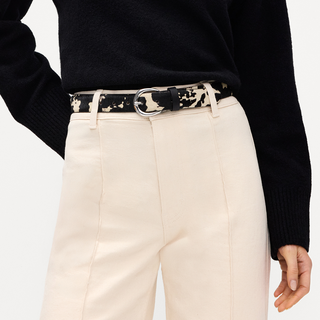 B&aelig;lte med sort‑hvidt ko‑pletm&oslash;nster og s&oslash;lvfarvet sp&aelig;nde, stylet med cremefarvede bukser og sort pullover.